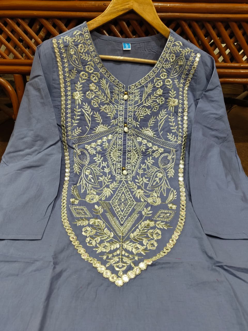 Close-up of grey embroidered kurta with intricate white threadwork and traditional patterns,