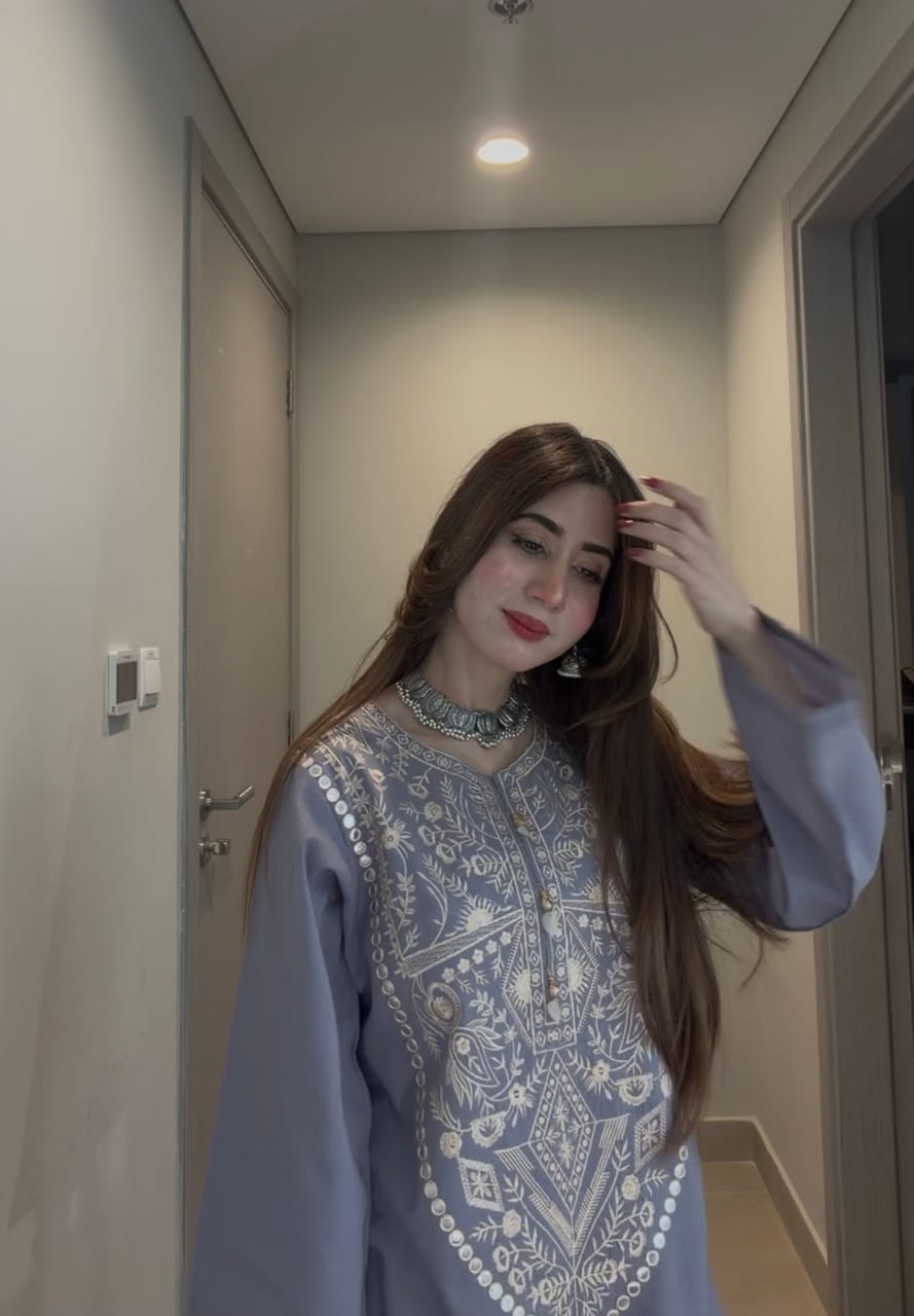 Woman wearing elegant grey ethnic kurta with detailed embroidery, styled with statement choker and long straight hair
