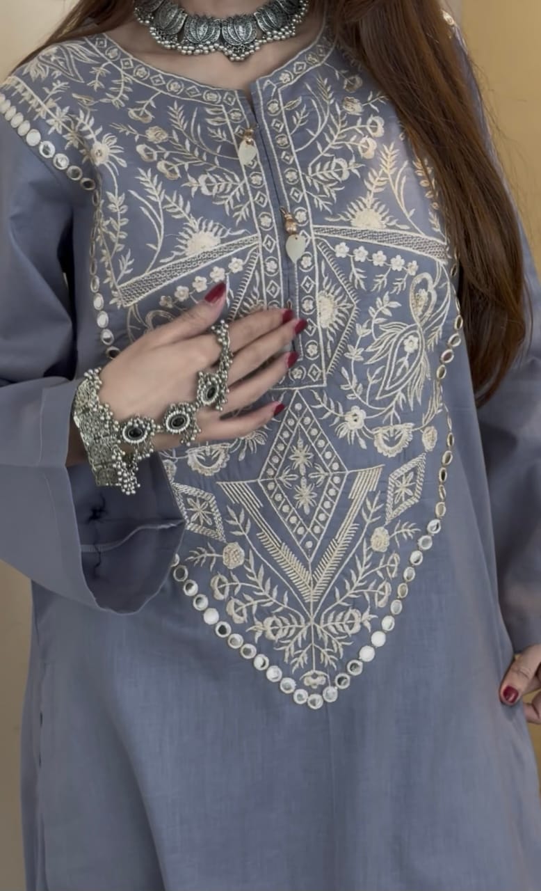 Close-up of grey embroidered kurta with intricate white threadwork and traditional patterns, paired with oxidized jewelry